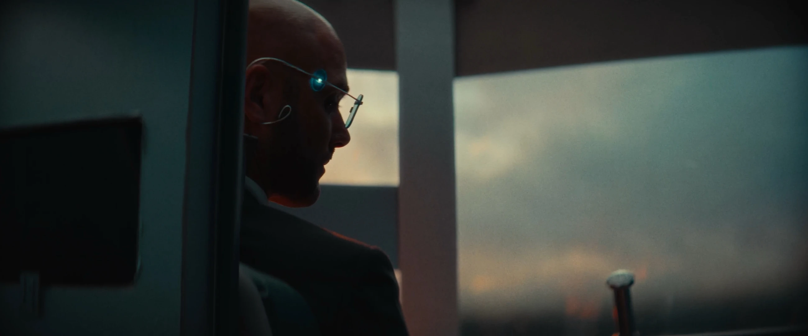 A man with a glowing earpiece looks across the city in Herr L.