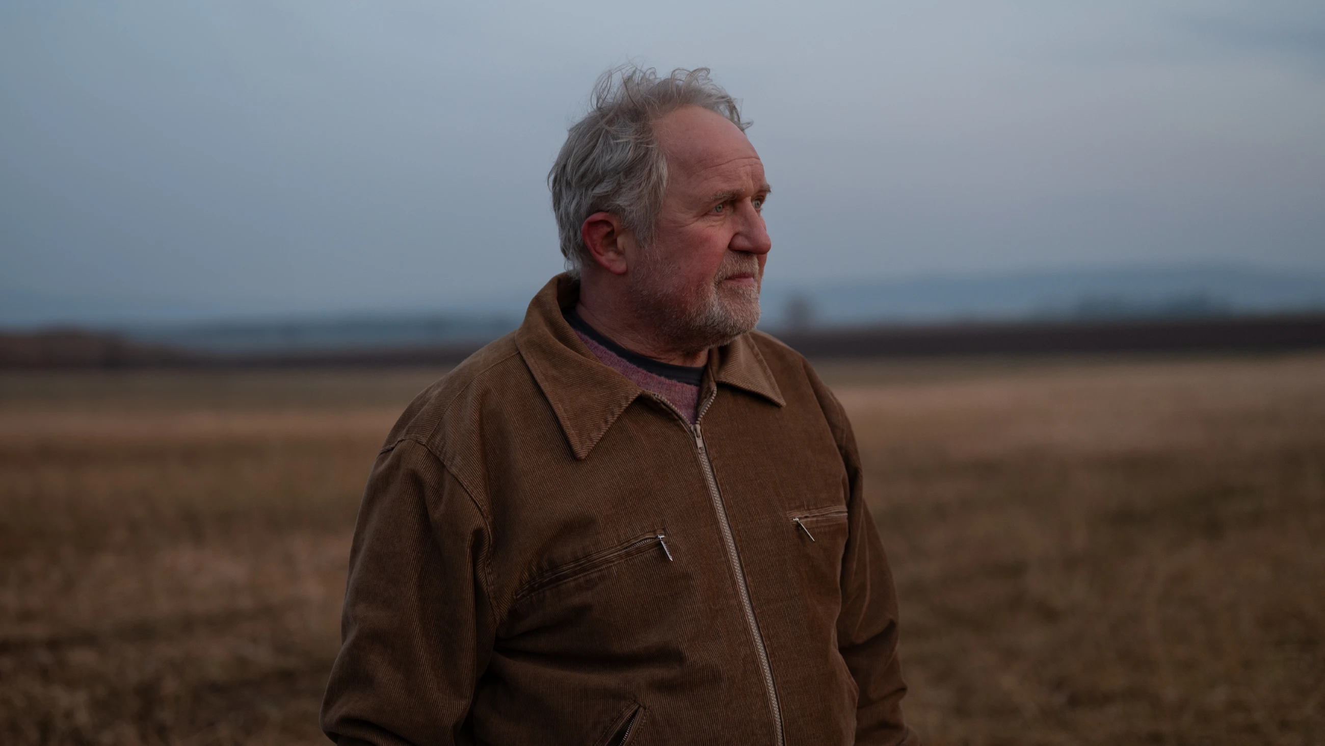 Kurt stands alone in an overcast field in Der verlorene Mann.