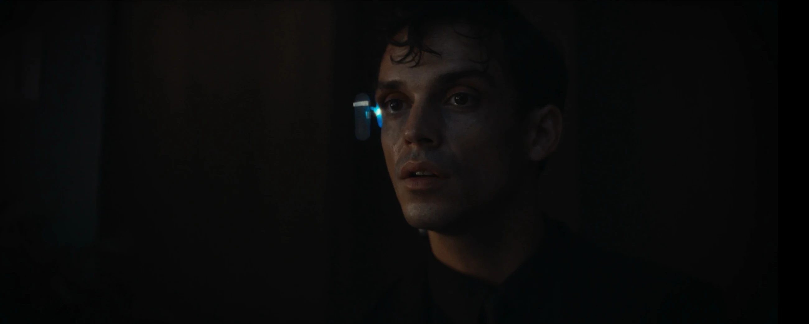 Close-up of a young man wearing a glowing earpiece in Herr L.
