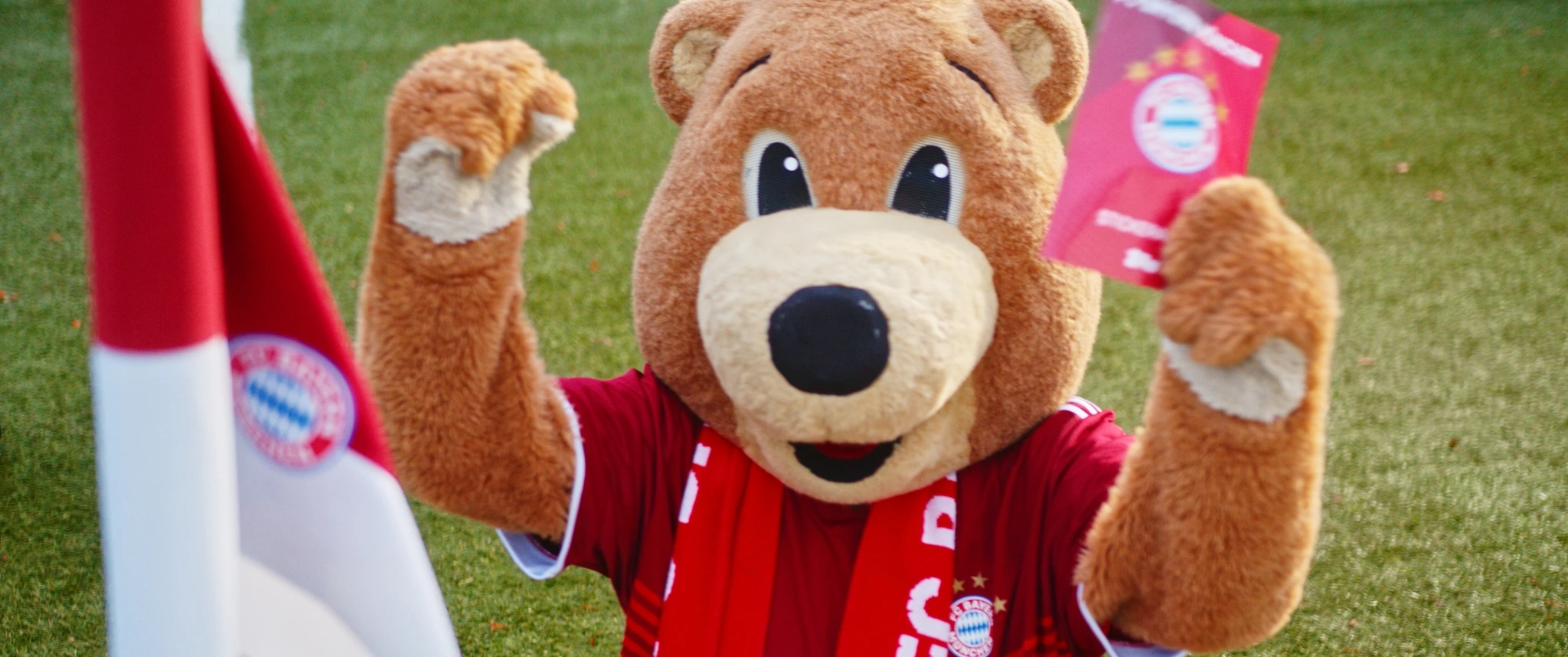 FC Bayern mascot Berni holds up a Topps trading card in the stadium.