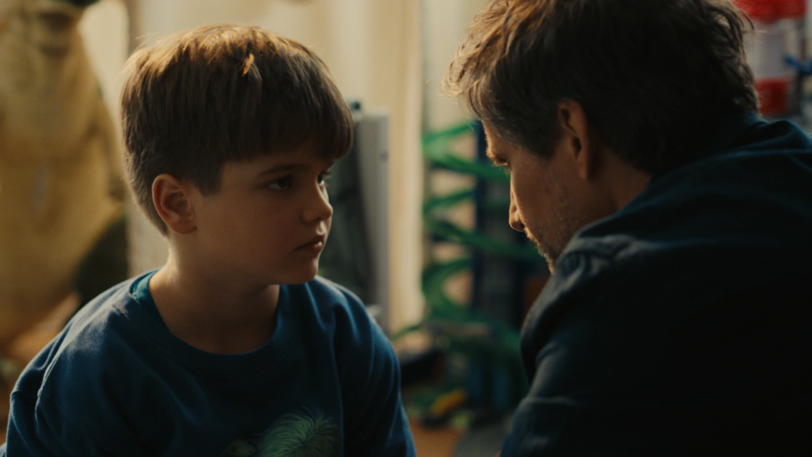 A boy and a man speak face to face at home in The Other gAIrl.