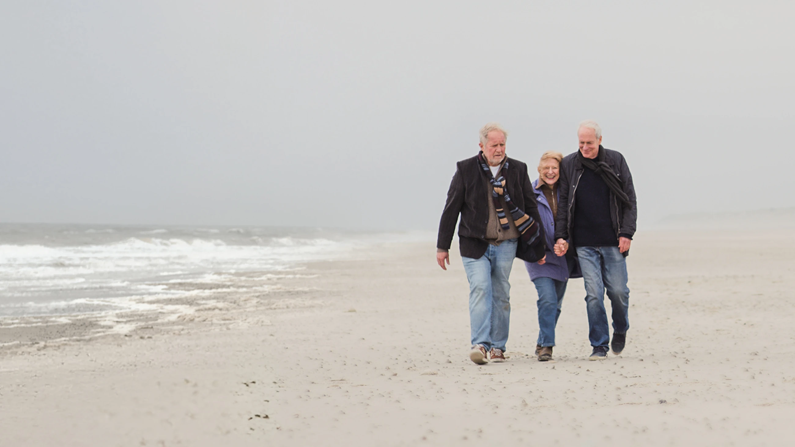 Three people walk together along a windy beach in Der verlorene Mann.
